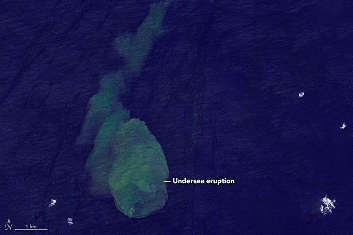 Satellite image of Kavachi submarine volcano in the Solomon Islands showing a green eruption plume rising through ocean waters.